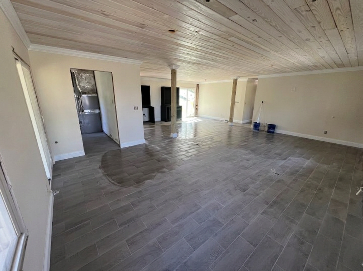 Finished open living area in Waverly GA with wood plank ceiling, white baseboard and crown trim, and new plank flooring