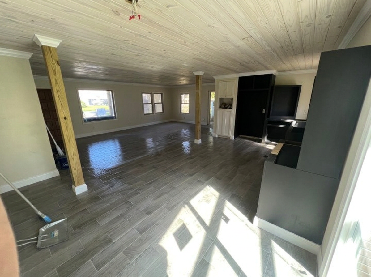 Finished open living room and kitchen in Waverly GA with wood plank ceiling, white baseboard and crown molding, and new wood-look plank flooring